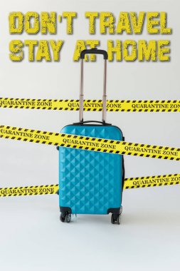 Mavi bavul sarı ve siyah tehlike uyarı bandı beyaz üzerinde, seyahat etmeyin, evde resimde kalın