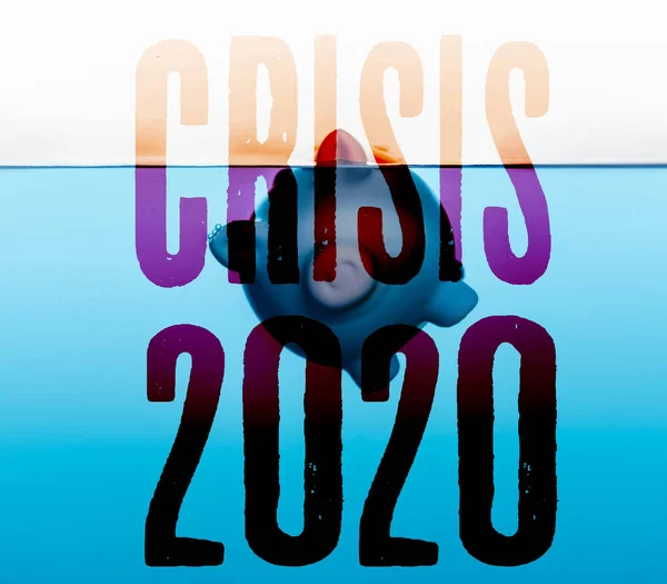 Mavi suyun altına giden kumbara beyaz, coronavirüs 2020 kriz konseptine izole edilmiş.