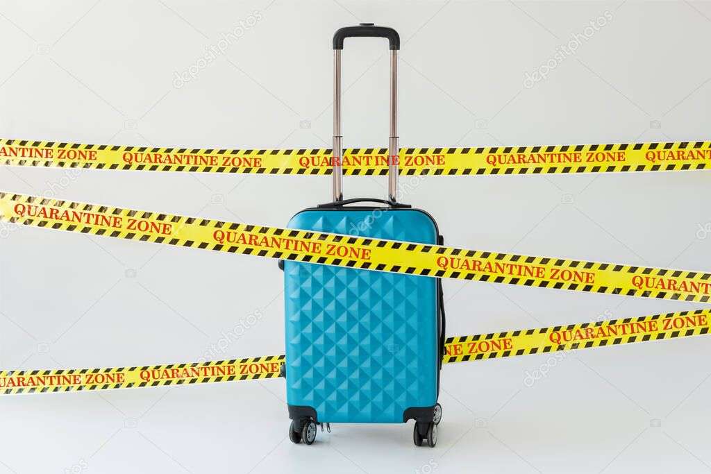 blue suitcase in yellow and black hazard warning safety tape with quarantine zone illustration on white, coronavirus concept