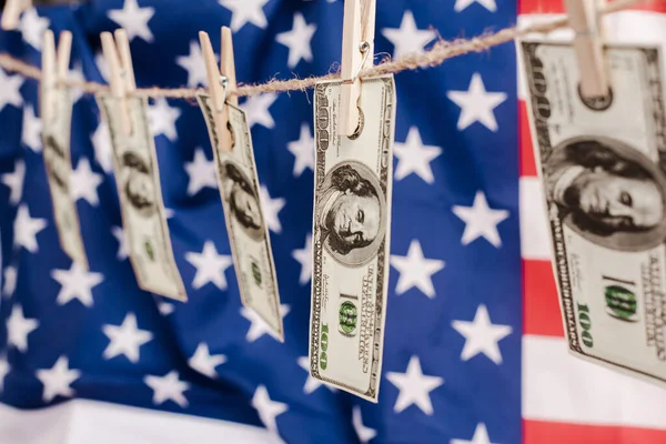 Foyer sélectif des billets en dollars accrochés à la corde sur fond de drapeau américain, concept de coronavirus — Photo de stock