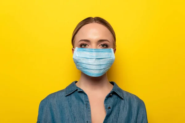 Jeune femme en masque médical sur fond jaune, concept de coronavirus — Photo de stock