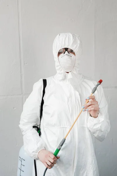 Person in white hazmat suit, respirator and goggles with disinfect in office, coronavirus concept — Stock Photo
