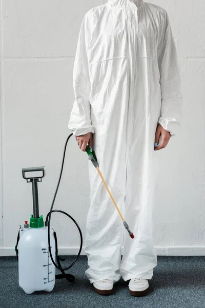 Ausgeschnittene Ansicht einer Person im weißen Warnanzug mit Desinfektionsmittel im Büro, Coronavirus-Konzept — Stockfoto