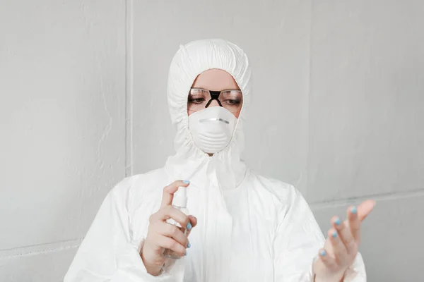 Foyer sélectif de la personne en combinaison blanche hazmat, respirateur et lunettes de désinfection des mains avec désinfectant pour les mains, concept de coronavirus — Photo de stock