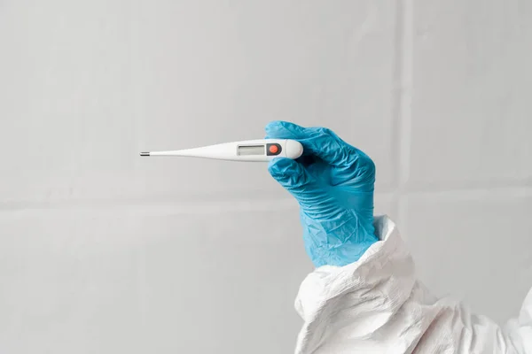 Cropped view of person in latex glove holding thermometer, coronavirus concept — Stock Photo