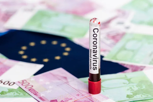 Selektiver Fokus auf Euro-Banknoten, Europaflagge und Coronavirus-Blutprobe — Stockfoto