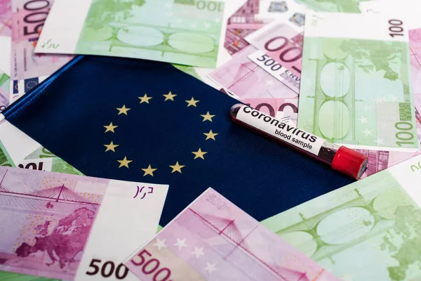 Billets en euros, drapeau européen et échantillon de sang de coronavirus — Photo de stock