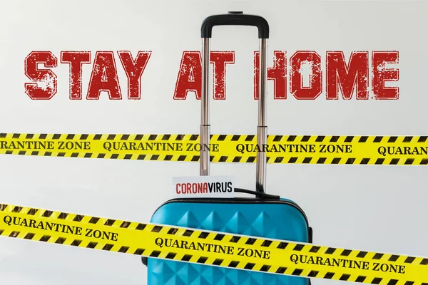Blauer Koffer mit Coronavirus-Karte in gelb-schwarzem Gefahrenwarnband isoliert auf weiß mit Bleiben zu Hause Abbildung — Stockfoto