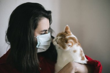 Tıbbi maskeli, kedili bir kız.