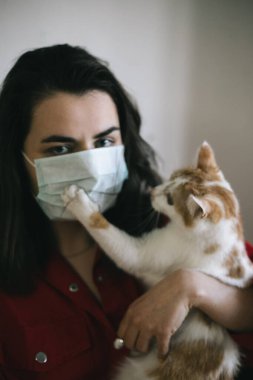 Tıbbi maskeli, kedili bir kız.