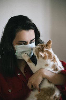 Tıbbi maskeli, kedili bir kız.