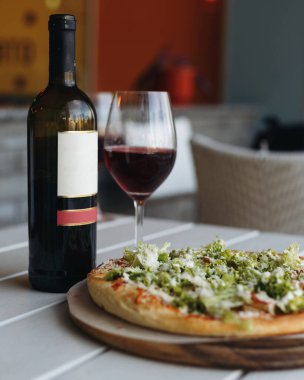 Bir şişe kırmızı şarap ve pizza.