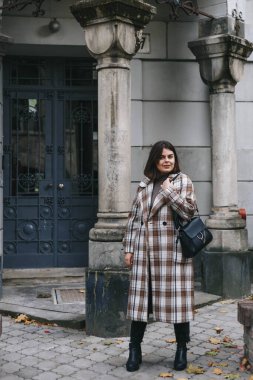 Eski bir binanın arka planında kareli ceketli bir kız.