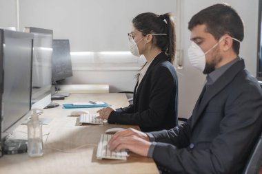 Coronavirus Ofis çalışanları Corona virüsü için maske takıyor. İş adamları sağlıklarını korumak ve korumak için maske takarlar. Ofis bilgisayarla çalışıyor. Evden çalışmak. 
