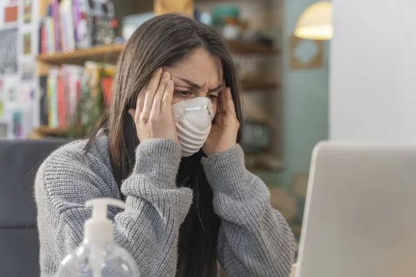 Coronavirus. Business woman working from home wearing protective mask. Business woman in quarantine for coronavirus wearing protective mask. Working from home.  Cleaning her hands with sanitizer gel.