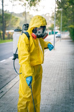 Coronavirus. Maske takıp sokakları temizleyen bir temizlik işçisi. Şehirdeki dezenfekte edilmiş şehirleri sterilize et. Coronavirüs 'e karşı dezenfekte. Kıyafet koruması. 