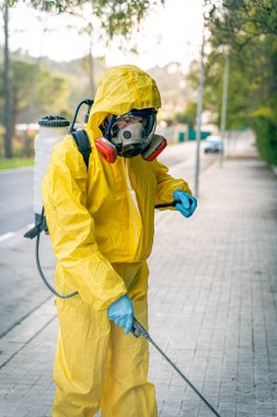 Coronavirus. Maske takıp sokakları temizleyen bir temizlik işçisi. Şehirdeki dezenfekte edilmiş şehirleri sterilize et. Coronavirüs 'e karşı dezenfekte. Kıyafet koruması. 