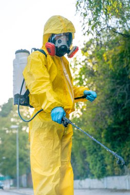 Coronavirus. Maske takıp sokakları temizleyen bir temizlik işçisi. Şehirdeki dezenfekte edilmiş şehirleri sterilize et. Coronavirüs 'e karşı dezenfekte. Kıyafet koruması. 