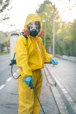 Coronavirus. Maske takıp sokakları temizleyen bir temizlik işçisi. Şehirdeki dezenfekte edilmiş şehirleri sterilize et. Coronavirüs 'e karşı dezenfekte. Kıyafet koruması. 