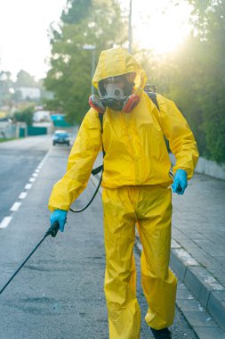 Coronavirus. Maske takıp sokakları temizleyen bir temizlik işçisi. Şehirdeki dezenfekte edilmiş şehirleri sterilize et. Coronavirüs 'e karşı dezenfekte. Kıyafet koruması. 