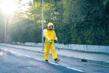 Coronavirus. Maske takıp sokakları temizleyen bir temizlik işçisi. Şehirdeki dezenfekte edilmiş şehirleri sterilize et. Coronavirüs 'e karşı dezenfekte. Kıyafet koruması. 