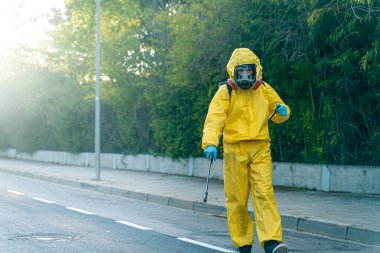 Coronavirus. Maske takıp sokakları temizleyen bir temizlik işçisi. Şehirdeki dezenfekte edilmiş şehirleri sterilize et. Coronavirüs 'e karşı dezenfekte. Kıyafet koruması. 