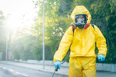 Coronavirus. Maske takıp sokakları temizleyen bir temizlik işçisi. Şehirdeki dezenfekte edilmiş şehirleri sterilize et. Coronavirüs 'e karşı dezenfekte. Kıyafet koruması. 