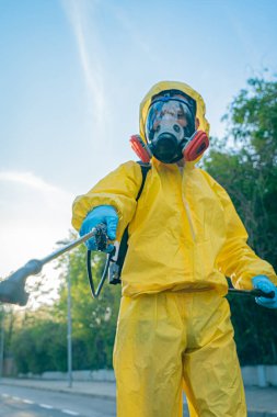 Coronavirus. Maske takıp sokakları temizleyen bir temizlik işçisi. Şehirdeki dezenfekte edilmiş şehirleri sterilize et. Coronavirüs 'e karşı dezenfekte. Kıyafet koruması. 