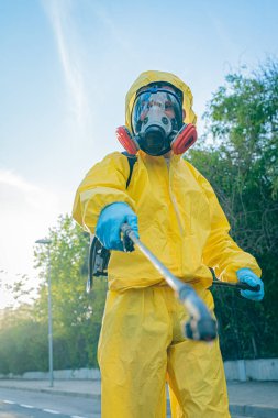 Coronavirus. Maske takıp sokakları temizleyen bir temizlik işçisi. Şehirdeki dezenfekte edilmiş şehirleri sterilize et. Coronavirüs 'e karşı dezenfekte. Kıyafet koruması. 