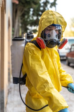 Coronavirus. Maske takıp sokakları temizleyen bir temizlik işçisi. Şehirdeki dezenfekte edilmiş şehirleri sterilize et. Coronavirüs 'e karşı dezenfekte. Kıyafet koruması. 