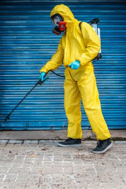 Coronavirus. Maske takıp sokakları temizleyen bir temizlik işçisi. Şehirdeki dezenfekte edilmiş şehirleri sterilize et. Coronavirüs 'e karşı dezenfekte. Kıyafet koruması. 