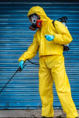 Coronavirus. Maske takıp sokakları temizleyen bir temizlik işçisi. Şehirdeki dezenfekte edilmiş şehirleri sterilize et. Coronavirüs 'e karşı dezenfekte. Kıyafet koruması. 