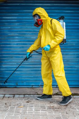Coronavirus. Maske takıp sokakları temizleyen bir temizlik işçisi. Şehirdeki dezenfekte edilmiş şehirleri sterilize et. Coronavirüs 'e karşı dezenfekte. Kıyafet koruması. 