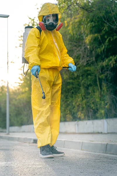 Coronavirus. A sanitation worker wearing a mask and cleaning the streets. Sterilize urban decontaminate city. Disinfecting against to the Coronavirus. Suit protection.