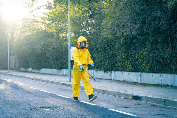 Coronavirus. A sanitation worker wearing a mask and cleaning the streets. Sterilize urban decontaminate city. Disinfecting against to the Coronavirus. Suit protection. 