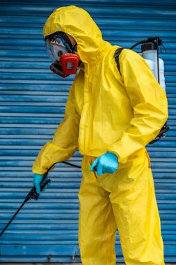 Coronavirus. Maske takıp sokakları temizleyen bir temizlik işçisi. Şehirdeki dezenfekte edilmiş şehirleri sterilize et. Coronavirüs 'e karşı dezenfekte. Kıyafet koruması. 