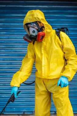 Coronavirus. Maske takıp sokakları temizleyen bir temizlik işçisi. Şehirdeki dezenfekte edilmiş şehirleri sterilize et. Coronavirüs 'e karşı dezenfekte. Kıyafet koruması. 