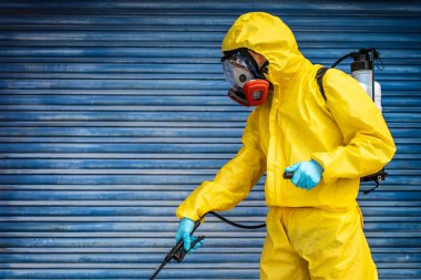 Coronavirus. Maske takıp sokakları temizleyen bir temizlik işçisi. Şehirdeki dezenfekte edilmiş şehirleri sterilize et. Coronavirüs 'e karşı dezenfekte. Kıyafet koruması. 