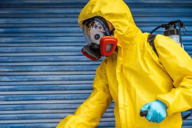 Coronavirus. Maske takıp sokakları temizleyen bir temizlik işçisi. Şehirdeki dezenfekte edilmiş şehirleri sterilize et. Coronavirüs 'e karşı dezenfekte. Kıyafet koruması. 