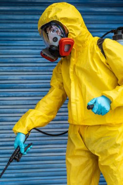 Coronavirus. Maske takıp sokakları temizleyen bir temizlik işçisi. Şehirdeki dezenfekte edilmiş şehirleri sterilize et. Coronavirüs 'e karşı dezenfekte. Kıyafet koruması. 