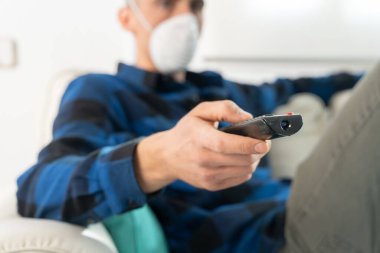 Coronavirus. Evde karantinada kanepede oturup televizyon izleyen bir çift. Kanepede oturan çift bulaşıcı hastalıktan korunmak için maske takıyor. Evde kal.. 