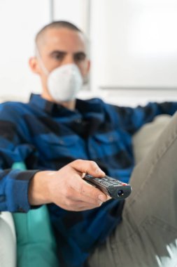 Coronavirus. Evde karantinada kanepede oturup televizyon izleyen bir çift. Kanepede oturan çift bulaşıcı hastalıktan korunmak için maske takıyor. Evde kal.. 