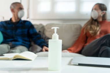 Coronavirus. Evde karantinada kanepede oturup televizyon izleyen bir çift. Kanepede oturan çift bulaşıcı hastalıktan korunmak için maske takıyor. Evde kal.. 