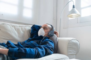 Coronavirus. Evde koruyucu maske takan bir adam. Koronavirüs yüzünden karantinaya alınan kadın ellerini dezenfektan jeliyle temizliyor. Evden çalışıyorum. Ellerini dezenfektan jeliyle temizle.. 