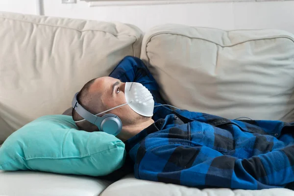 Coronavirus. Man at home wearing protective mask. Woman in quarantine for coronavirus on the couch cleaning her hands with sanitizer gel. Working from home. Clean your hands with sanitizer gel.