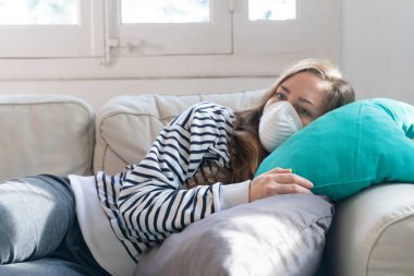 Coronavirus. Evde koruyucu maske takan bir kadın. Koronavirüs yüzünden karantinaya alınan kadın ellerini dezenfektan jeliyle temizliyor. Evden çalışıyorum. Ellerini dezenfektan jeliyle temizle.. 