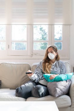 Coronavirus. Evde koruyucu maske takan bir kadın. Koronavirüs yüzünden karantinaya alınan kadın ellerini dezenfektan jeliyle temizliyor. Evden çalışıyorum. Ellerini dezenfektan jeliyle temizle.. 