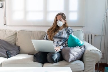 Coronavirus. Evde koruyucu maske takan bir kadın. Koronavirüs yüzünden karantinaya alınan kadın ellerini dezenfektan jeliyle temizliyor. Evden çalışıyorum. Ellerini dezenfektan jeliyle temizle.. 