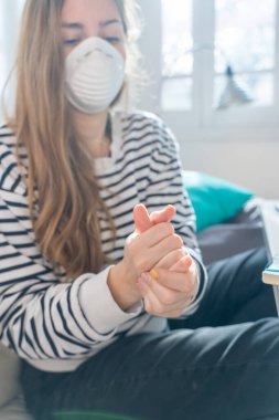Coronavirus. Evde koruyucu maske takan bir kadın. Koronavirüs yüzünden karantinaya alınan kadın ellerini dezenfektan jeliyle temizliyor. Evden çalışıyorum. Ellerini dezenfektan jeliyle temizle.. 