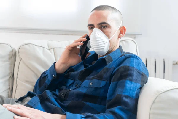 Coronavirus. Man at home wearing protective mask. Woman in quarantine for coronavirus on the couch cleaning her hands with sanitizer gel. Working from home. Clean your hands with sanitizer gel.